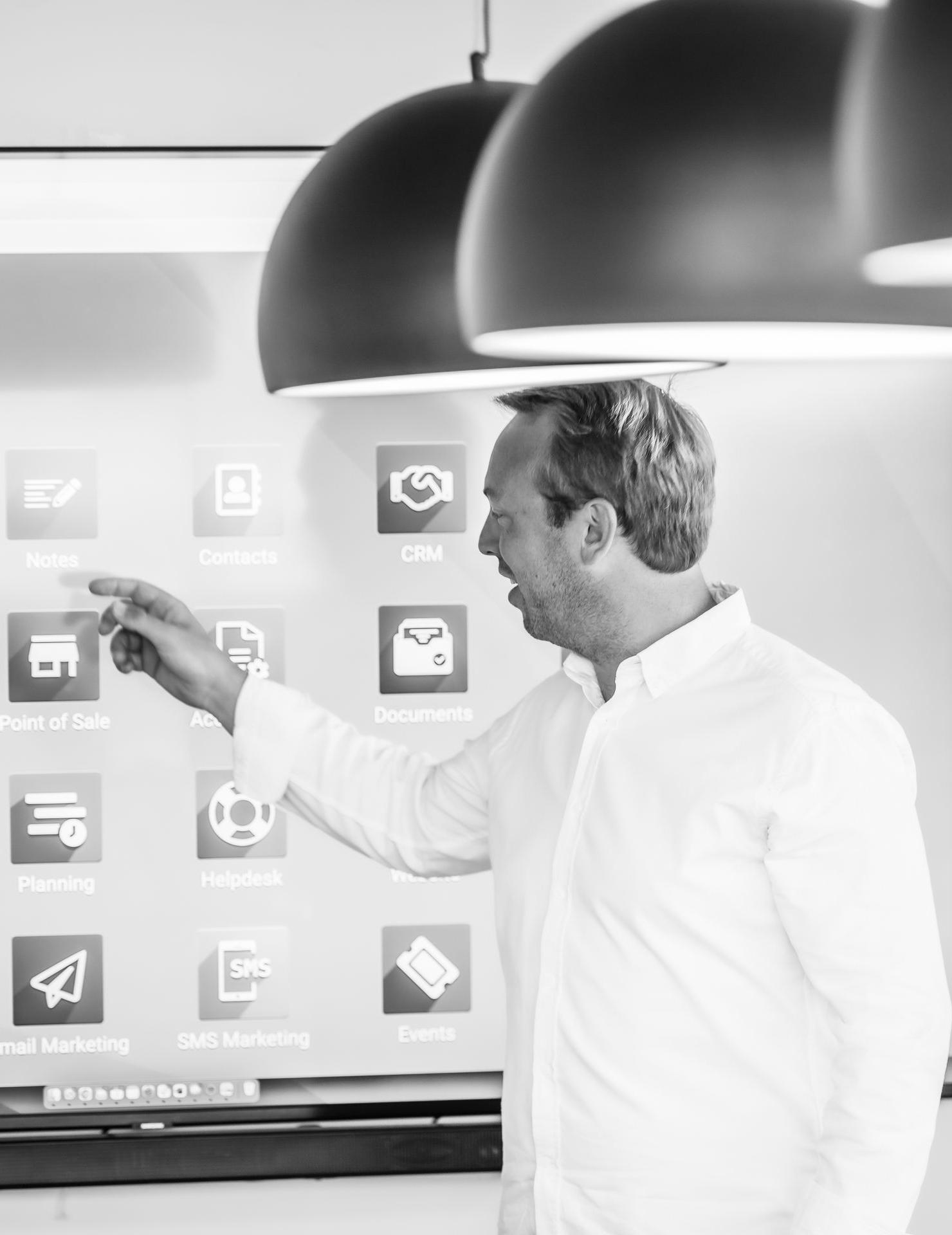 notre fondateur Arnaud Percy fondateur de the service company partenaire odoo indique les applications odoo sur un écran dans une pièce avec des grosses lampes
